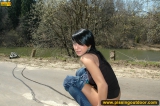Teen brunette pissing on asphalt path outdoor