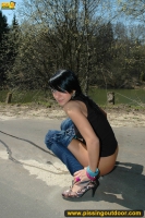 Teen brunette pissing on asphalt path outdoor