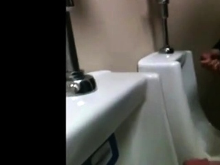 two slim dicks getting wanked at the urinals